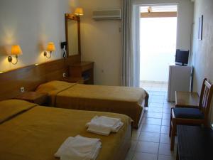 a hotel room with two beds and a television at Andreolas Beach Hotel in Laganas