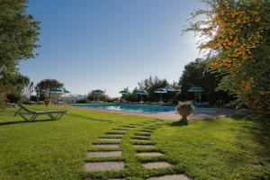 a garden with a stone path next to a swimming pool at Villa Borgo San Pietro in Cortona