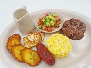 a plate of breakfast food with sausage eggs potatoes and a salad at Hotel Plaza San Martin in Tegucigalpa