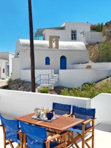 a table and chairs on a balcony with a house at Psathi Blue Beta in Kimolos