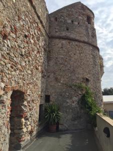 
a stone walled building with a clock on it at Al Castello Affittacamere in Pietra Ligure
