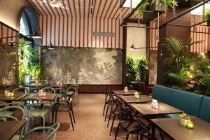 a restaurant with tables and chairs and plants at Hotel Sanpi Milano in Milan