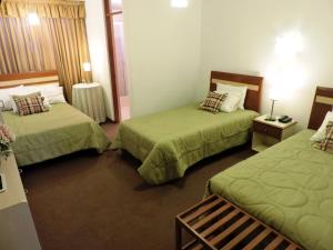 um quarto de hotel com duas camas e uma mesa em Hotel San Andres em Arequipa
