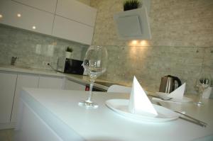 ケメロヴォにあるАпартаменты ул Спортивная 17 Люкс с Джакузиの白いテーブルとワイン1杯付きのキッチン