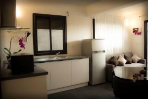 a kitchen with a sink and a refrigerator and a couch at Ti Kaz Bonheur in Saint-Gilles-les Hauts
