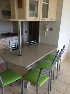 una cocina con mesa y sillas con asientos verdes en Departamento Pinares del Canelillo, en Algarrobo