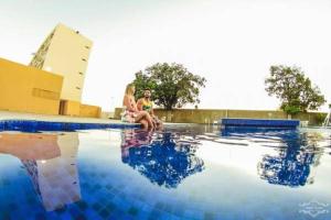 duas mulheres sentadas ao lado de uma piscina em Hotel do Grande Rio em Petrolina