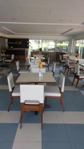 Un comedor con mesas y sillas blancas. en Apartamento Pontal Beach., en Río de Janeiro