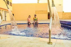 Ein Mann und eine Frau, die im Schwimmbad sitzen in der Unterkunft Hotel do Grande Rio in Petrolina