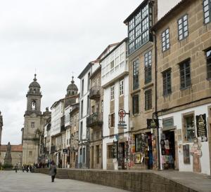 a woman walking down a street with buildings and a clock tower at Apartamentos Domus Stellae in Santiago de Compostela
