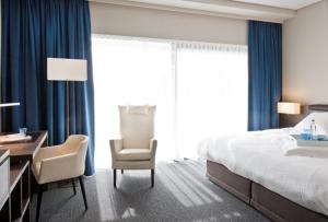 DeerlijkにあるBlue Woods Hotel - Deerlijkのベッド、デスク、椅子が備わるホテルルームです。