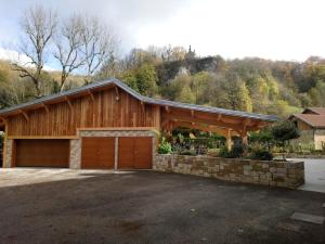 uma casa com uma garagem de madeira com uma parede de pedra em L'auberge Des 3 Ponts em Cusance