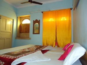 - une chambre avec un lit et un rideau jaune dans l'établissement Ganesh Guest House, à Jaisalmer