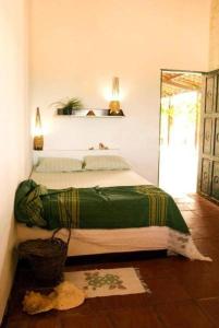 a bedroom with a bed with a green blanket on it at Pousada e Restaurante Tremembé in Icapuí