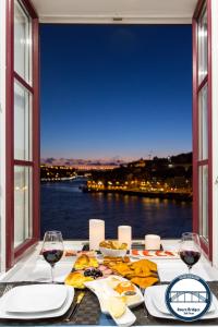 a table with glasses of wine and a view of the water at Douro Riverside Apartments in Vila Nova de Gaia