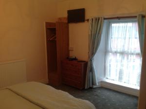 a bedroom with a bed and a dresser and a window at Sheehans On Main Street in Kenmare