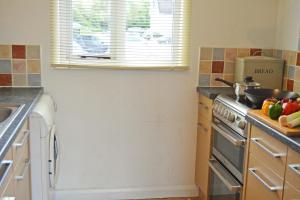 a kitchen with a stove and a sink and a window at Shelduck Lodge in South Cerney