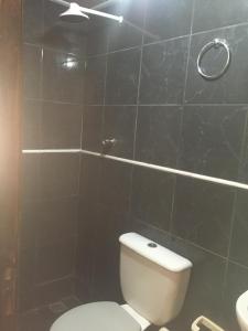 a bathroom with a toilet and a black tiled wall at Hotel Fortaleza III Manaus in Manaus