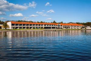 a building with an orange roof next to a body of water at Millennium Hotel & Resort Manuels Taupo in Taupo
