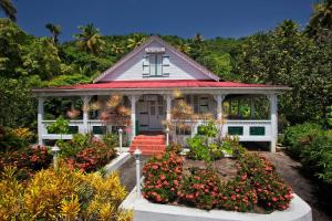 a small white house with flowers in front of it at La Dauphine Estate in Soufrière