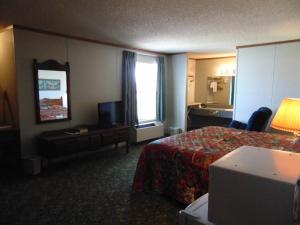 a hotel room with a bed and a television at Heritage House Inn in Muleshoe