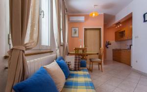een woonkamer met een blauwe bank en een keuken bij Apartments Luka 2 in Baška