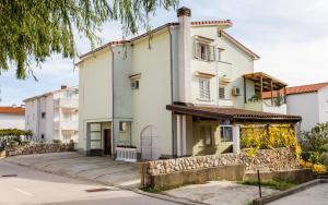 een groot wit huis met een stenen muur bij Apartments Luka 2 in Baška