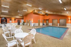 ein Poolzimmer mit weißen Tischen und Stühlen sowie einem Pool in der Unterkunft Super 8 by Wyndham Brookings in Brookings
