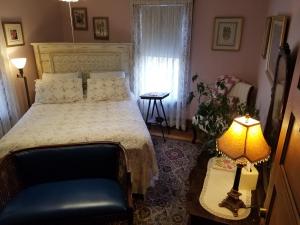 a bedroom with a bed and a table with a lamp at Rose & Thistle Bed & Breakfast in Cooperstown