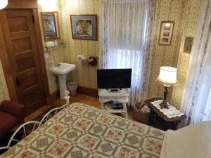 una camera con letto, lavandino e televisore di Rose & Thistle Bed & Breakfast a Cooperstown