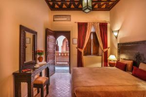 a bedroom with a bed and a table and a mirror at Riad & Spa Bahia Salam in Marrakesh