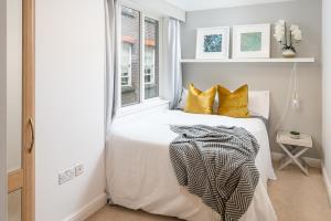 a white bedroom with a bed with yellow pillows at Square Mile Residences in London