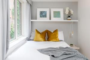 a bedroom with a bed with yellow pillows and a window at Square Mile Residences in London