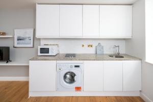 a white kitchen with a washing machine in it at Square Mile Residences in London