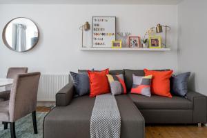 a living room with a gray couch with colorful pillows at Square Mile Residences in London