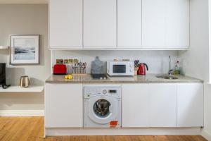 a kitchen with a washing machine and a microwave at Square Mile Residences in London