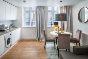 a kitchen and living room with a table and chairs at Square Mile Residences in London