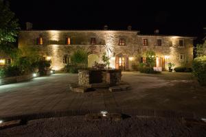 a large stone building with a fountain at night at Villa Borgo San Pietro in Cortona