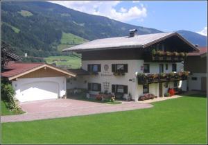 a large white house with a garage and green grass at Habachschmied Familie Gruber in Bramberg am Wildkogel