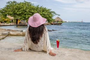 a woman in a pink hat sitting on the beach at Serene by the Sea in Savaneta