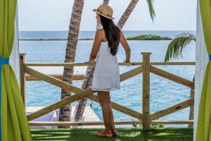 a woman standing on a fence looking out at the ocean at Serene by the Sea in Savaneta