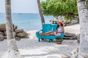 a woman sitting in a chair on the beach at Serene by the Sea in Savaneta