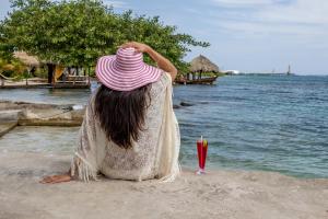 a woman with a pink hat sitting on the beach at Serene by the Sea in Savaneta