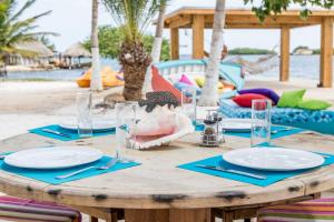 a wooden table with plates and glasses on a beach at Serene by the Sea in Savaneta