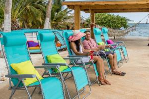 a man and woman sitting in chairs on the beach at Serene by the Sea in Savaneta