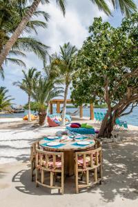 a wooden table on a beach with palm trees at Serene by the Sea in Savaneta