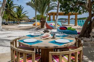 a wooden table with plates and glasses on a beach at Serene by the Sea in Savaneta