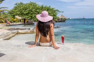 a woman in a pink hat sitting on a beach at Serene by the Sea in Savaneta