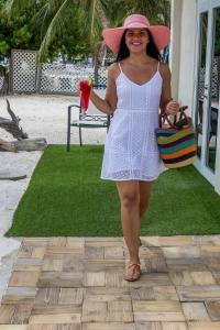 a woman in a white dress and a pink hat at Serene by the Sea in Savaneta