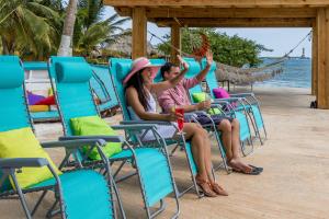 a man and woman sitting in chairs on the beach at Serene by the Sea in Savaneta